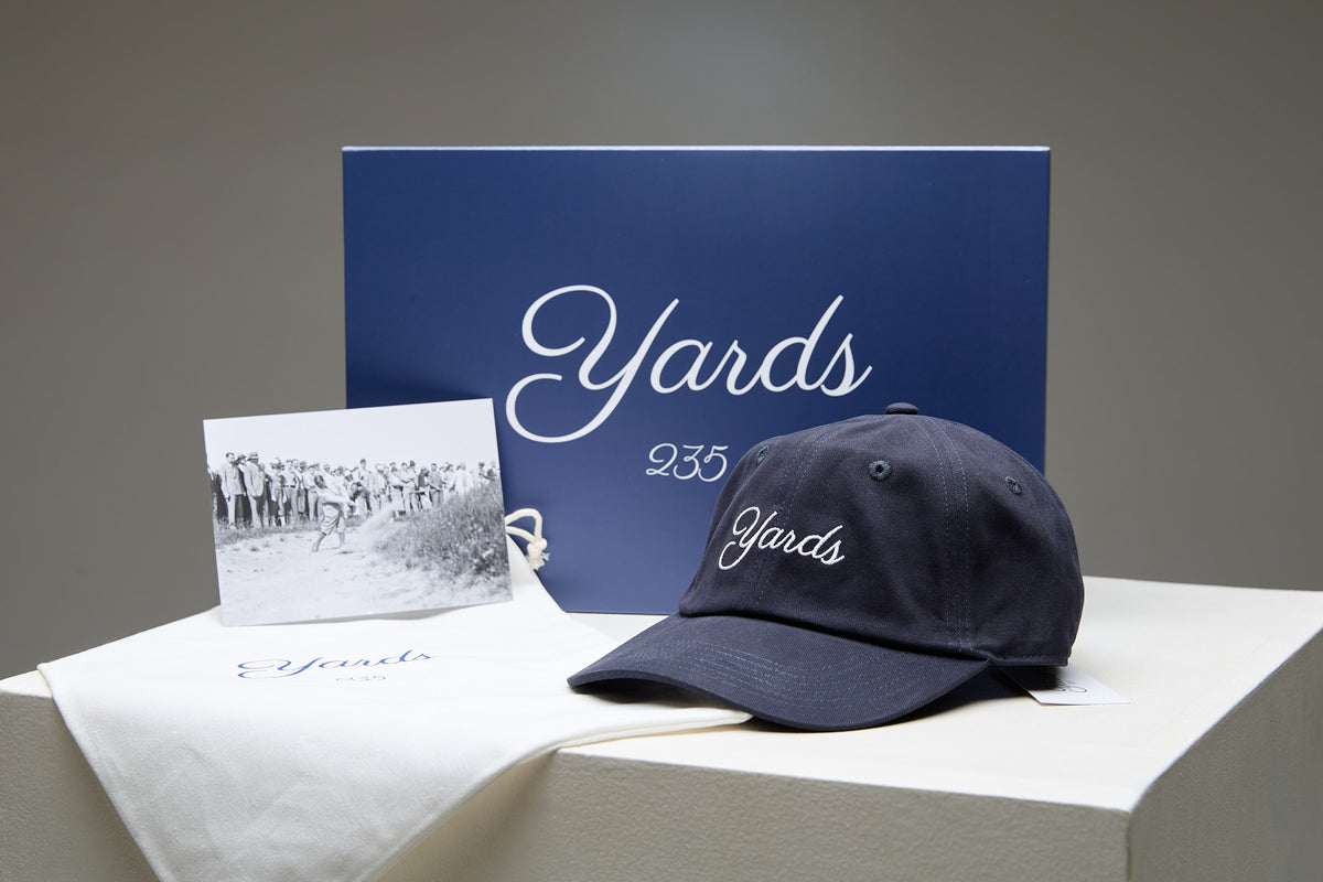 Navy cap and photo with 'Yards' branding on a gray background